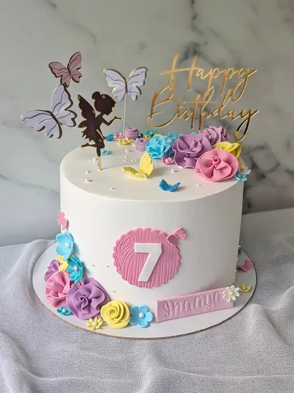 A pretty floral and fairy cake for a 7th birthday. The design features a fairy silhouette, colorful flowers, and delicate butterflies.