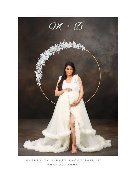 A serene solo portrait of a mom-to-be in a white gown, standing before a simple, elegant floral hoop. The minimalist setup puts all the focus on her and the beauty of her pregnancy.