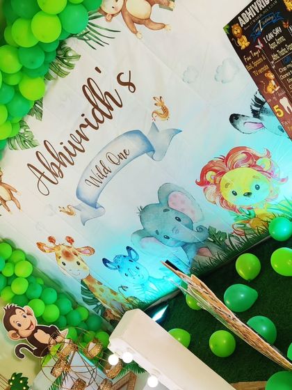 A close-up of a jungle-themed backdrop, featuring cute cartoon animals and a 'Wild One' banner.