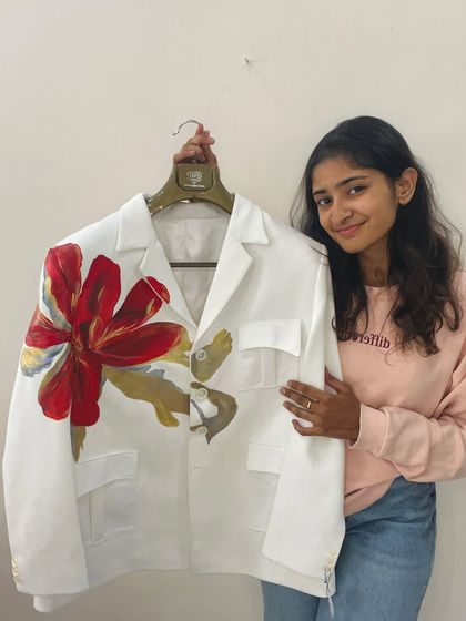 Me holding up a finished blazer with a large, bold red flower. I love how a single, powerful design can completely transform a garment.