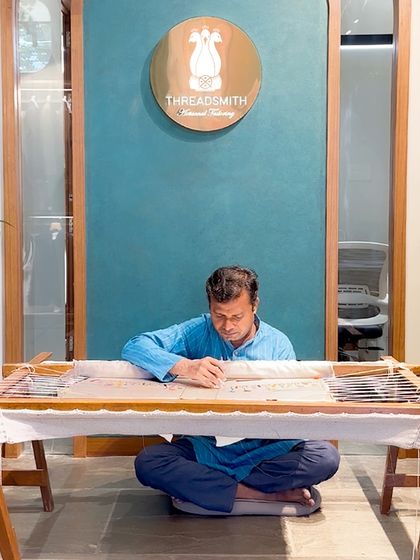 An artisan at work on a traditional embroidery frame, or adda. This is where your stories and our craftsmanship come together to create something truly unique.