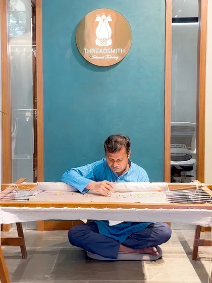 An artisan at work on a traditional embroidery frame, or adda. This is where your stories and our craftsmanship come together to create something truly unique.