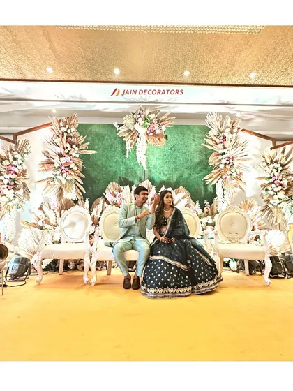 A chic and rustic engagement stage. The backdrop of green foliage is accented with arrangements of dried palms and pastel flowers, with elegant vintage seating for the couple.