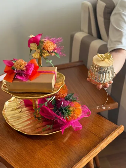 Showcasing another element of customization, this image shows a beautiful candle being added to the tiered platter arrangement, enhancing its value as both a gift and a decor piece.