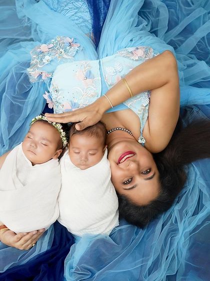 A mother's embrace with her newborn twins. This creative overhead shot, with the babies nestled against their mom on a sea of blue fabric, is a beautiful and artistic way to capture this unique bond.
