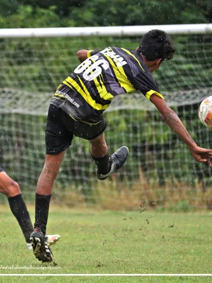A player leaps to control a high ball with his chest during a B Division match, demonstrating excellent technique under pressure.
