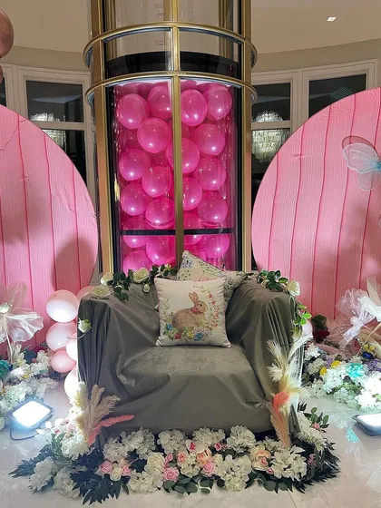 I can even incorporate venue features into the design, like this elevator filled with pink balloons. The comfortable armchair, surrounded by flowers, creates a perfect throne for the mom-to-be.