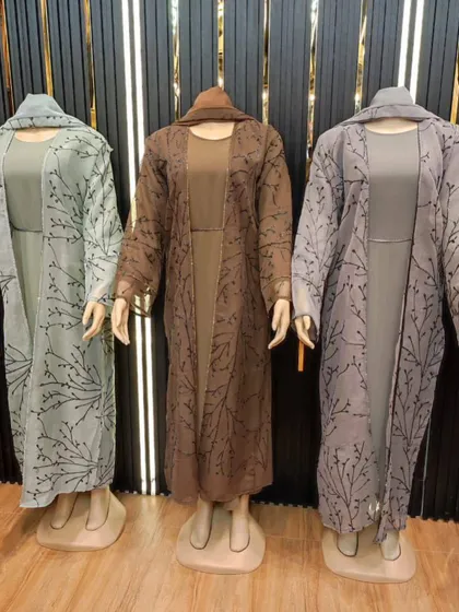 These three piece abaya sets come with an inner dress and a sheer outer layer with delicate patterns. Available in soft green, brown, and grey, they offer a complete, coordinated modest look.