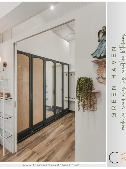 A wider perspective of the "Green Haven" project, showing how the walk-in wardrobe with its sliding door integrates into the larger room. The design uses natural materials and textures to create a warm, inviting passage.