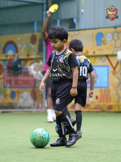 A young player with the ball at his feet, learning the basics of dribbling in a supportive environment.