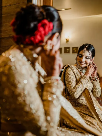 A mirror shot capturing a quiet moment of preparation. Her smile reflects her happiness, and her makeup looks flawless.