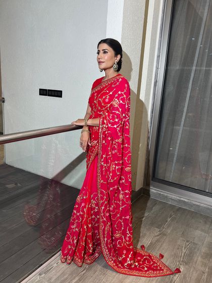 A classic red saree paired with an elegant, clean bun. This timeless hairstyle is perfect for showcasing statement jewelry and a beautiful blouse neckline.