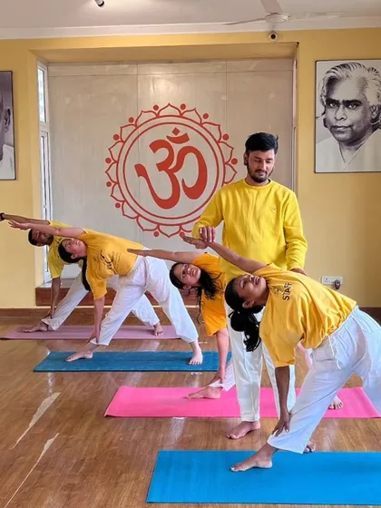 An instructor makes a subtle adjustment to a student's Triangle Pose, a common practice in our classes to help you experience the full expression of the asana.