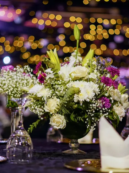 A close-up of a table setting, with a beautiful floral centerpiece captured against a soft-focus background of golden bokeh lights, showcasing the romantic ambiance.