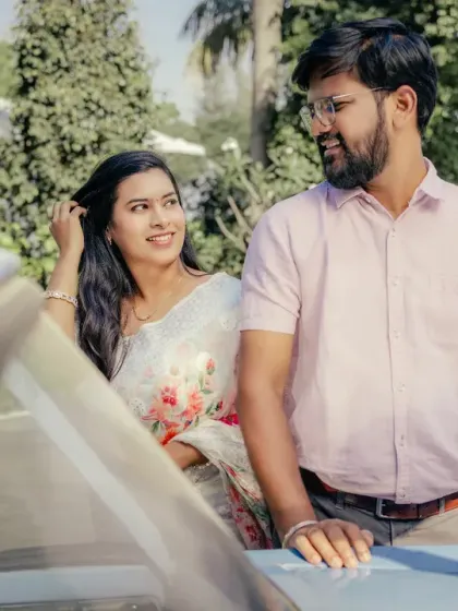 Capturing the candid, in-between moments of a pre-wedding shoot. The couple shares a natural glance next to a vintage car, creating a relaxed and authentic photograph.