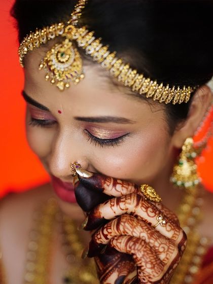 A close up of the bride's delicate features, enhanced by soft, glowing makeup and a traditional matha patti.