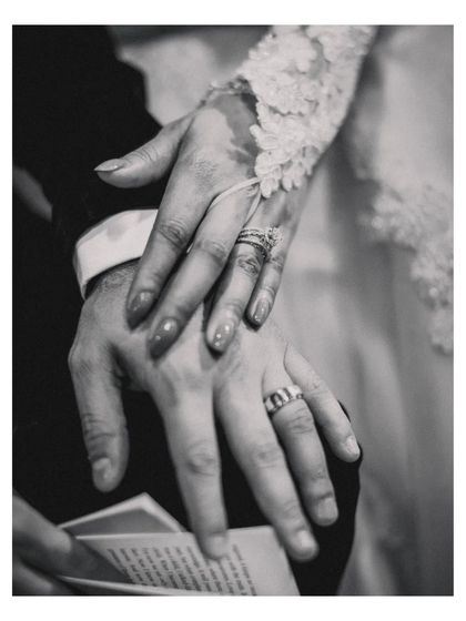 A black and white detail shot of the couple's hands, showing their wedding rings, symbolizing their new union.