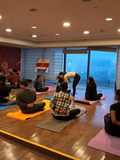 Offering a gentle assist in a seated twist during a corporate wellness event. These sessions are tailored to address the specific needs of office workers.