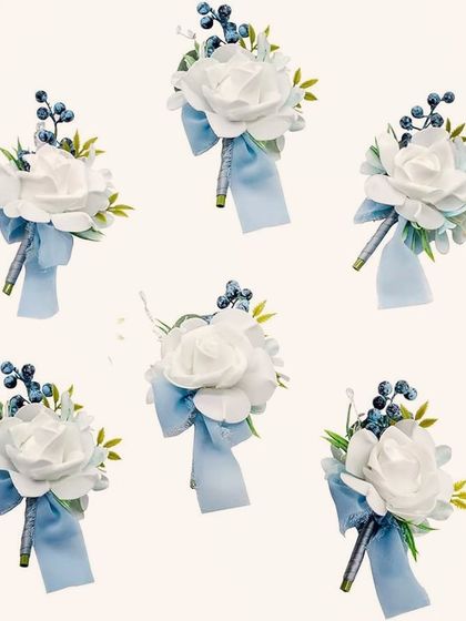 Here is a set of six matching boutonnieres ready for the groom and his groomsmen. Each spray features a single white foam rose accented with blue berries and a light blue ribbon, ensuring the whole party has a coordinated look.