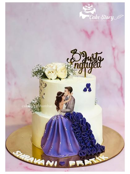A beautiful two-tier 'Just Engaged' cake. The design features a print of a romantic couple, with the bride's purple gown created from flowing fondant ruffles.
