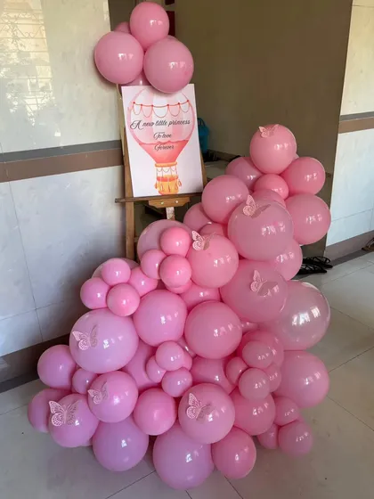 A simple yet beautiful welcome stand for a butterfly-themed party, with a custom sign and an arrangement of pink balloons with butterfly stickers.