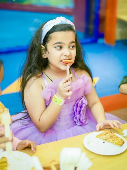 A young guest enjoying a slice of pizza at our cafe.