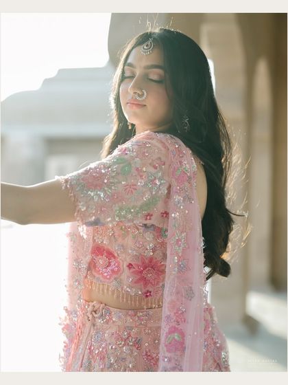 Bathed in the golden hour light of Jaipur. This portrait captures the bride in a moment of serene beauty, with the warm light enhancing the soft pink of her lehenga.
