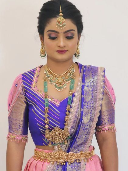 A full look at a beautiful South Indian bride. The makeup is perfectly balanced with her elaborate jewellery and colorful outfit, creating a harmonious and elegant appearance.