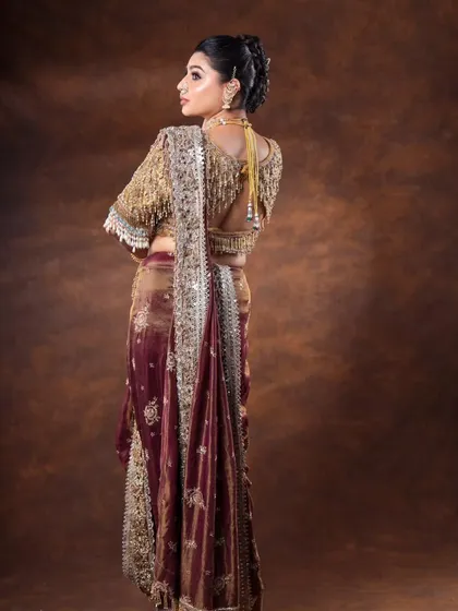 A back view of the outfit, focusing on the detailed blouse design and the elegant drape of the saree.