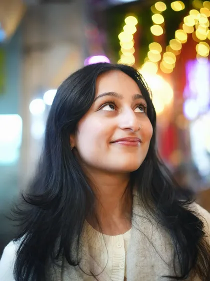 A dreamy night portrait with the subject looking up at the festive lights. The beautiful bokeh effect creates a magical, celebratory mood.