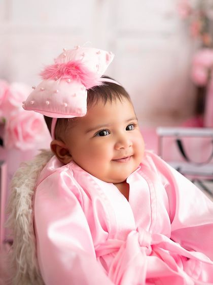 A beautiful close-up of this baby's happy face, with a big pink bow in her hair.
