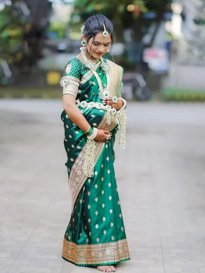 A full-length portrait of the mother-to-be in her beautiful green saree and floral jewelry, taken during an outdoor session as part of her baby shower celebration.