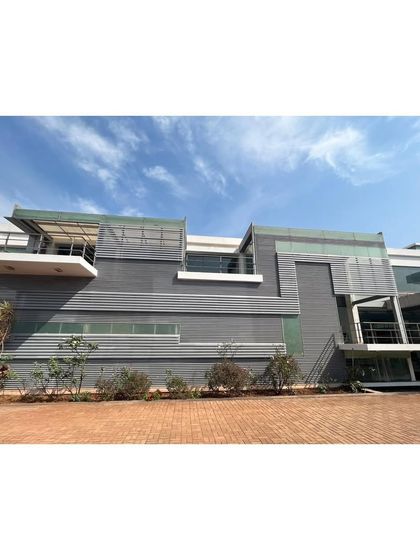 The facade of the office campus is a complex composition of grey metal panels, glass, and open terraces, creating a modern and sophisticated corporate identity.