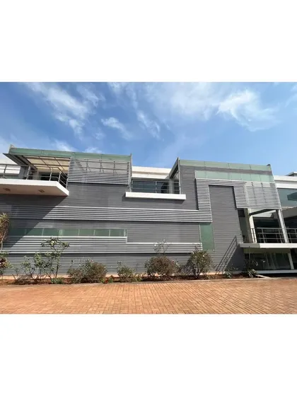 The facade of the office campus is a complex composition of grey metal panels, glass, and open terraces, creating a modern and sophisticated corporate identity.