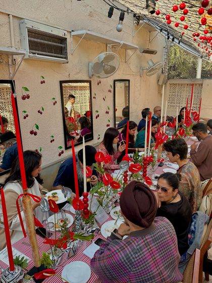 Guests enjoying the festive atmosphere at our Christmas brunch. The long table is decorated with red candles and anthuriums, creating a warm and celebratory vibe.