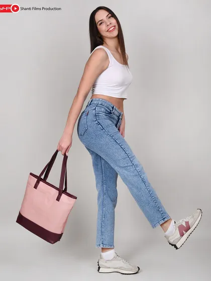 This playful, high-key shot of a model with a canvas tote bag is designed to appeal to a younger demographic. The clean background keeps the focus on the product's color and shape.