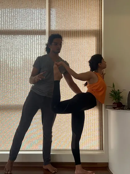 An instructor offers verbal cues and physical guidance for Natarajasana. This image captures the focus and communication that are central to our teaching methodology.