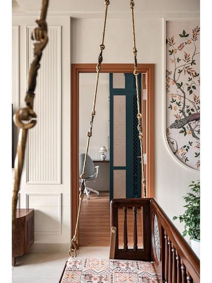 A view from the living room, looking through the doorway into the master bedroom. The traditional brass-detailed swing in the foreground beautifully frames the modern, serene bedroom beyond.