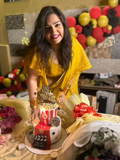 Another joyful shot of Snehil Mehra with her Bollywood-themed birthday cake, surrounded by flowers and gifts.