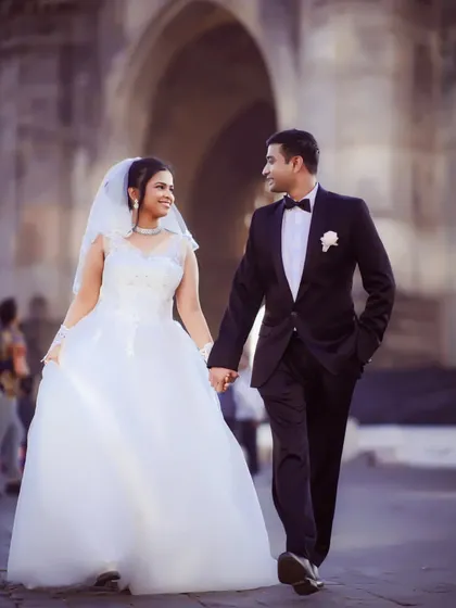 A beautiful shot of a couple in their wedding attire walking hand-in-hand, captured in a classic, elegant style.