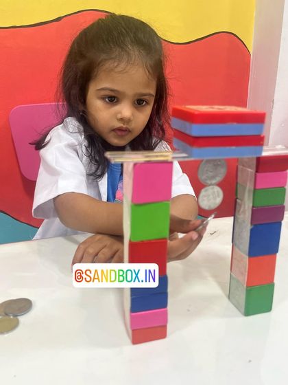 How strong is a magnetic field? This student is carefully building a bridge with magnetic blocks, testing how many coins can be suspended in mid-air by the force of the magnets.