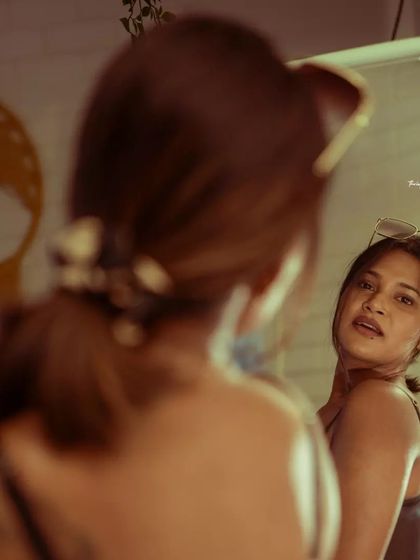 A simple, clean mirror portrait. The focus is on the subject's expression in the reflection, creating a personal and introspective feel.