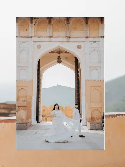An artistic shot framing the couple within a grand archway at Amer Fort, emphasizing the scale and beauty of the location.