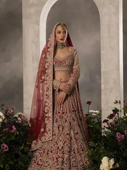 A full-length shot of a bridal lehenga set against a floral and arched backdrop. My creative direction and styling aimed to create a romantic and grand setting that complements the opulence of the hand-embroidered bridal couture.