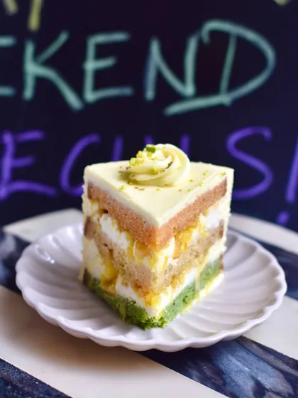 A slice of our Pistachio, Saffron & Orange Birthday Cake, a modern take on classic Indian flavours.