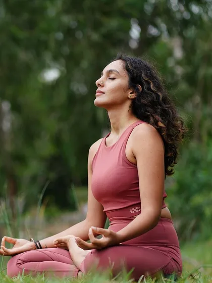 Seated in meditation in a lush green park. This image is paired with reflections on creating healthy morning and night routines to achieve your goals and live a more peaceful life.