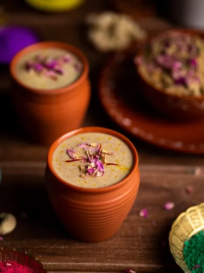 Thandai served in traditional clay kulhads, garnished with rose petals. This styling choice adds an element of rustic authenticity to the image.