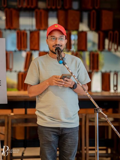 A performer in a red cap focuses on his phone as he shares his poem. Our casual and supportive environment encourages even first-timers to take the stage.