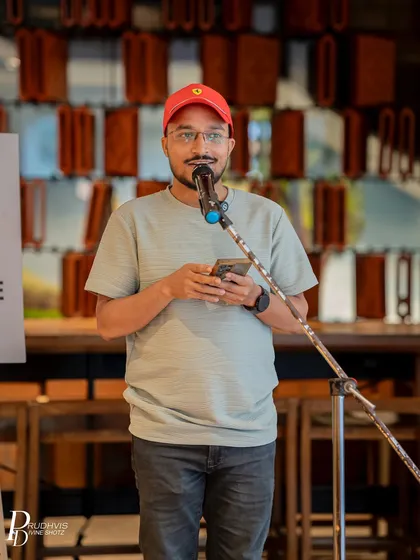 A performer in a red cap focuses on his phone as he shares his poem. Our casual and supportive environment encourages even first-timers to take the stage.