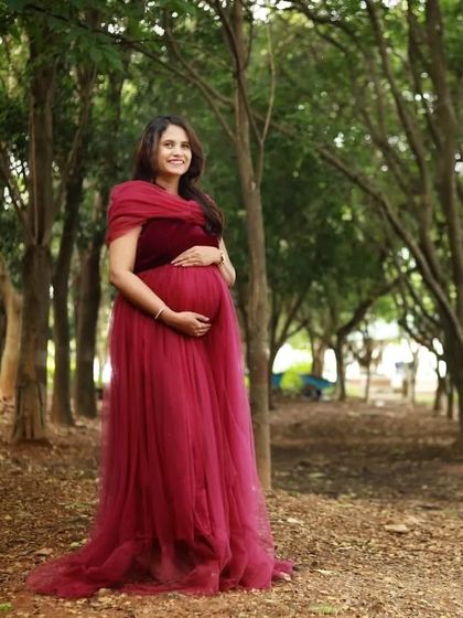 A beautiful, serene portrait of an expecting mother in a maroon gown. The natural forest setting provides a peaceful backdrop for this maternity photo.